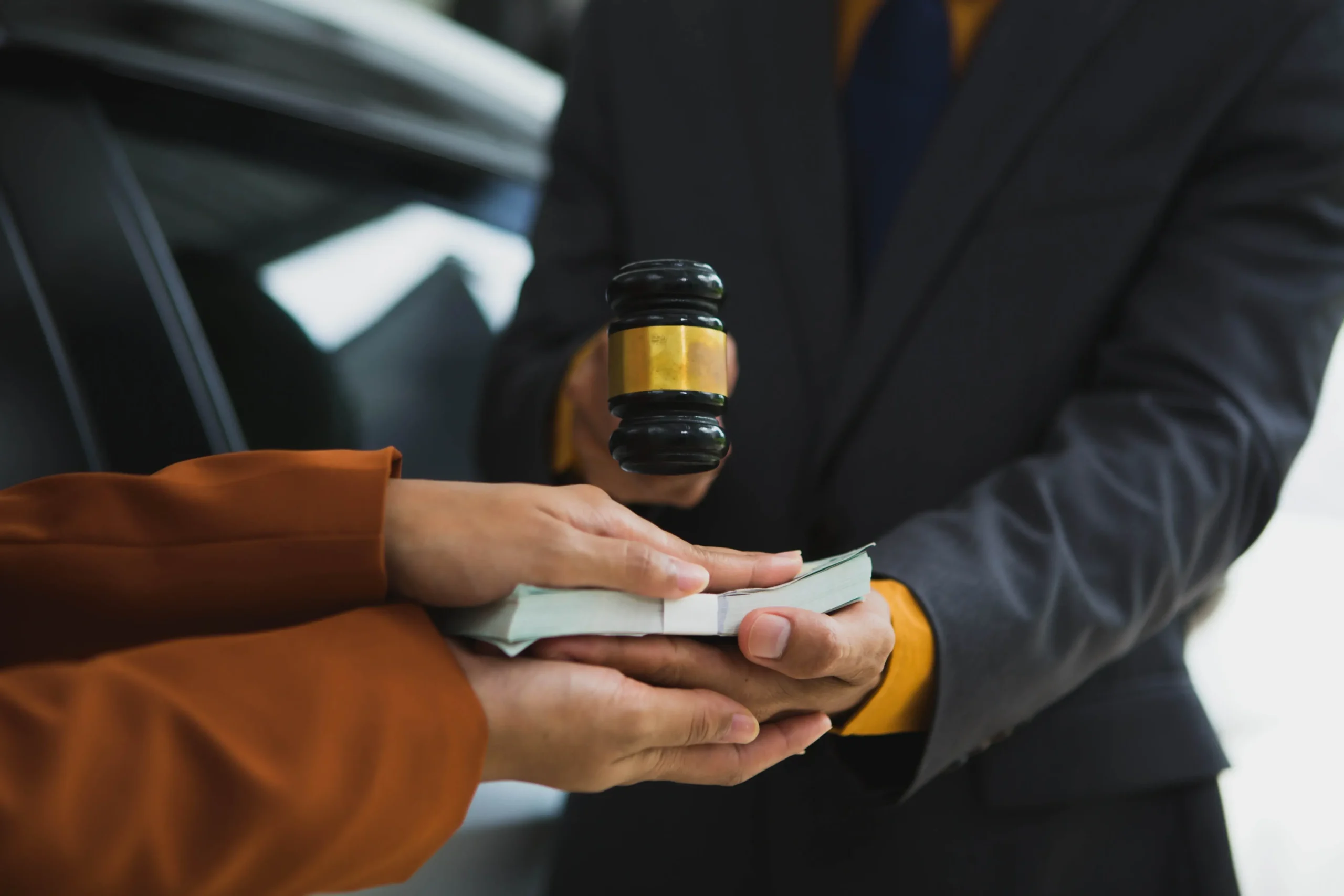 Lawyer handing cash to a client across a desk with a gavel nearby