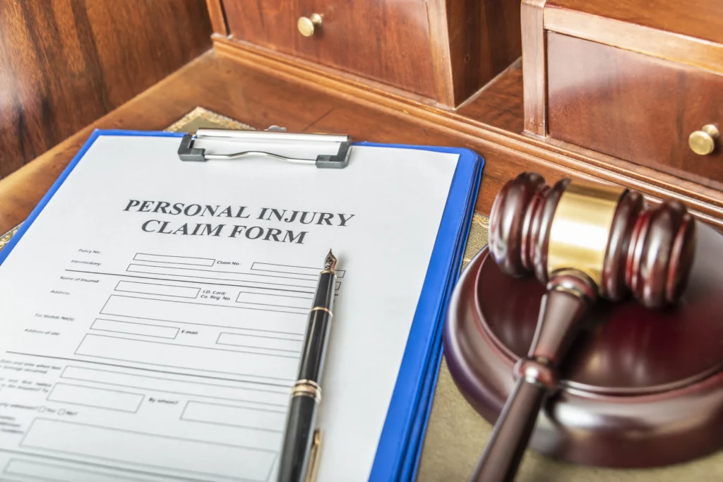 Personal injury claim form on a clipboard next to a gavel and pen on a legal desk.