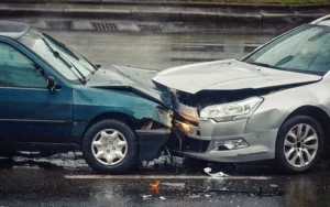 Two cars involved in a head-on collision on a wet road, showing significant front-end damage.