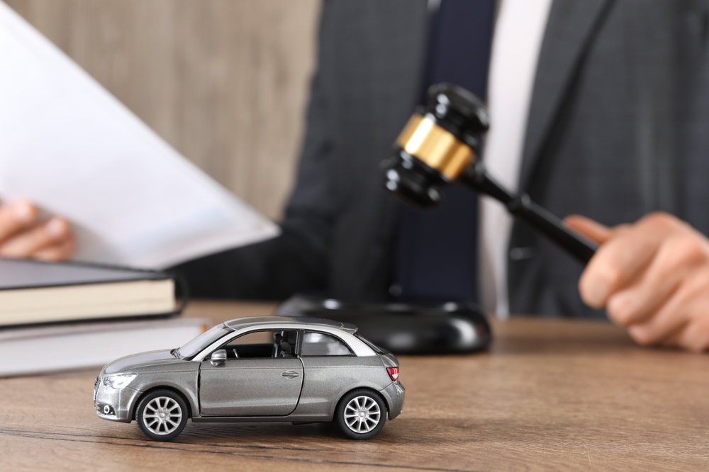 Judge's gavel beside a small model car and legal documents