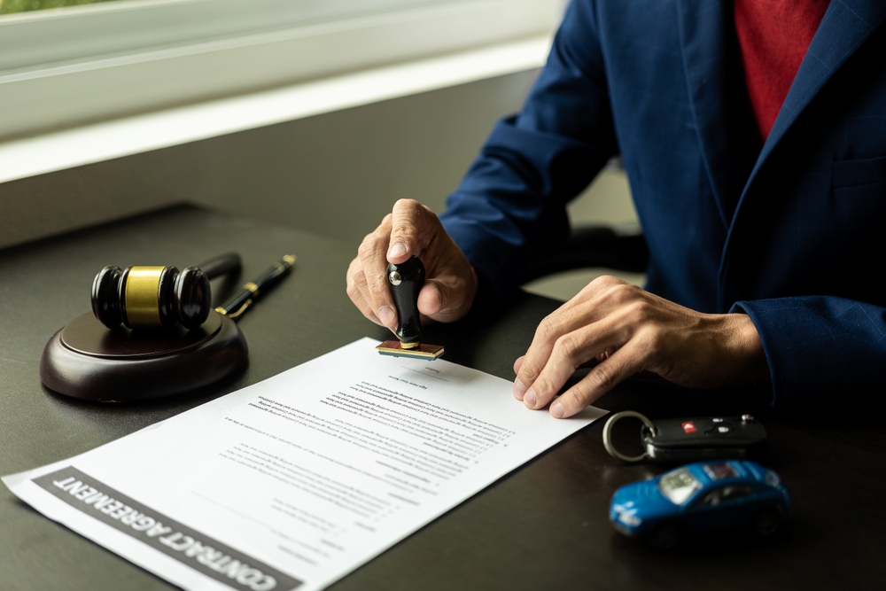 Lawyer reviewing and signing a settlement document next to a gavel