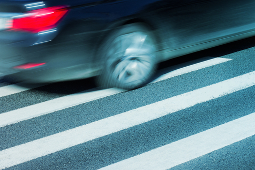 A car drives on the road beside a white line, highlighting the importance of safety. Houston Pedestrian Accident Lawyer.