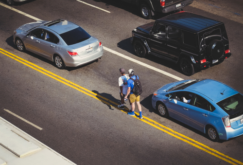 Two people standing on the side of a busy road, highlighting the need for a Houston Pedestrian Accident Lawyer.