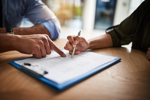 A couple signing a contract with a Houston Rideshare Accident Lawyer for legal representation.