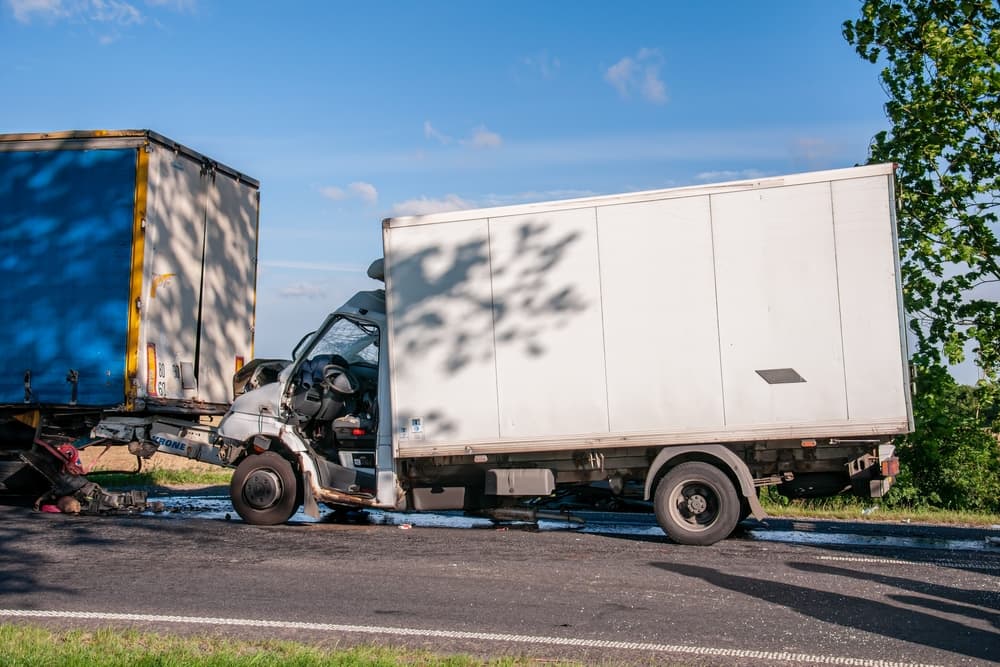 White box truck damaged after a collision with a trailer on a roadway