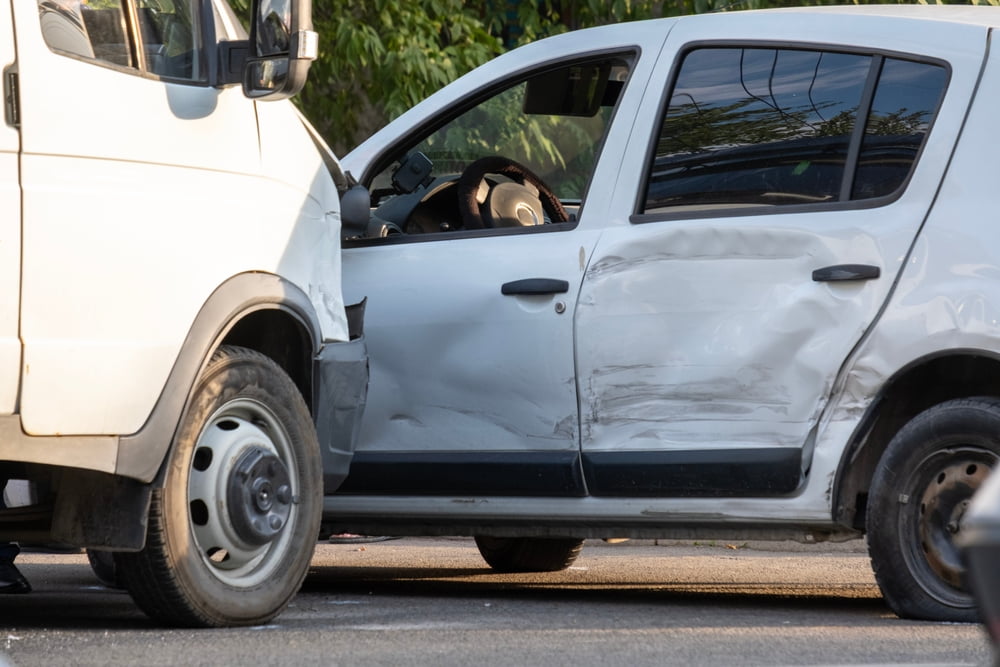 White commercial van after a side-impact collision with a passenger car